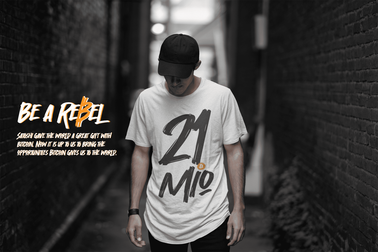 White guy standing in an alley wearing a black hat and a white bitcoin t-shirt.