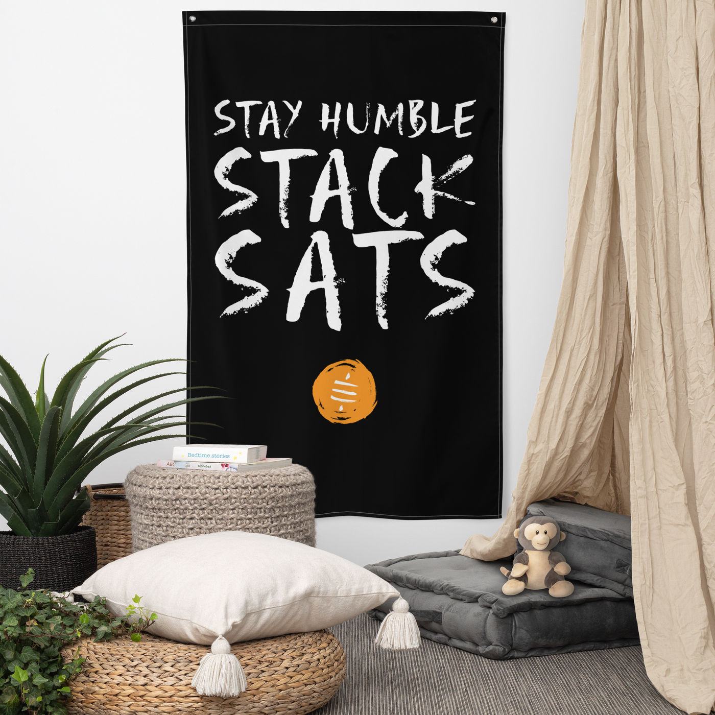 Stay Humble Stack Sats bitcoin flag, hanging on a wall above a seating corner.
