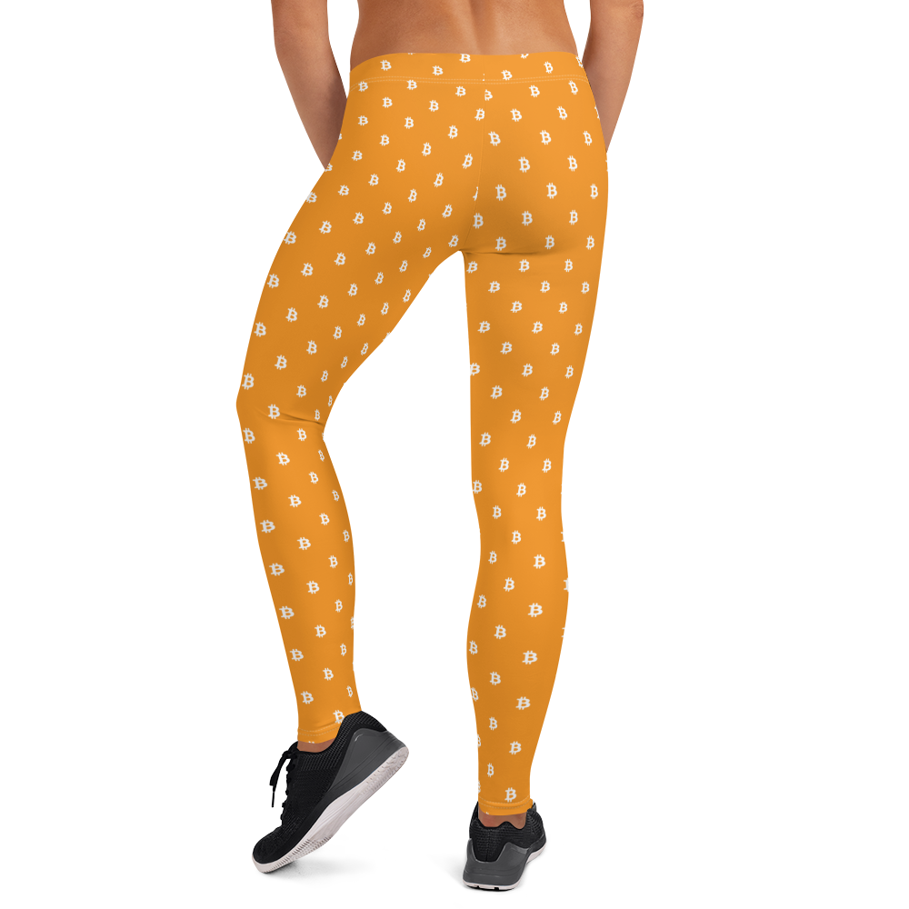 Back view of a woman wearing orange bitcoin leggings.