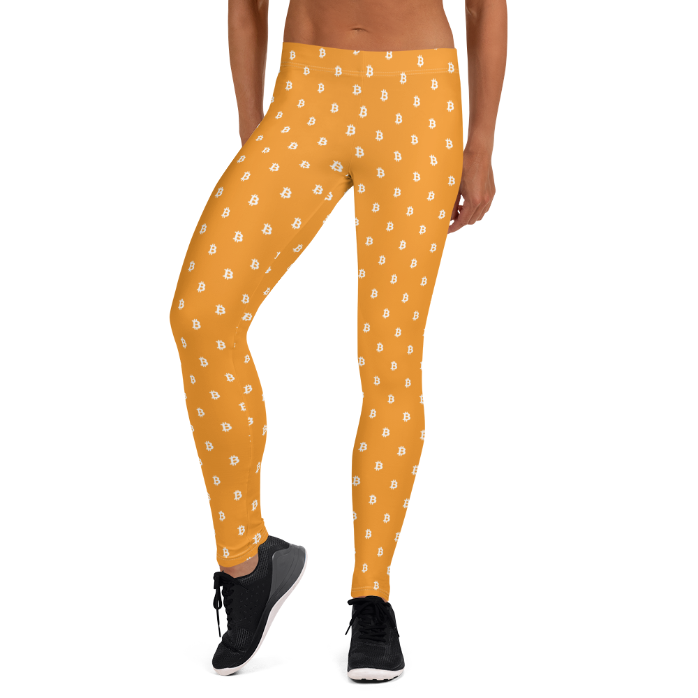 Front view of a woman wearing orange bitcoin leggings.