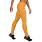 Side view of a woman wearing orange bitcoin leggings.