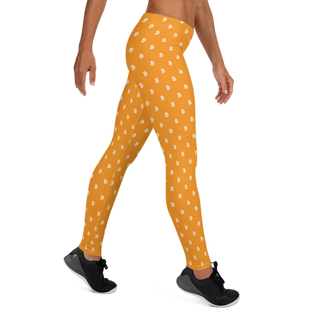 Side view of a woman wearing orange bitcoin leggings.