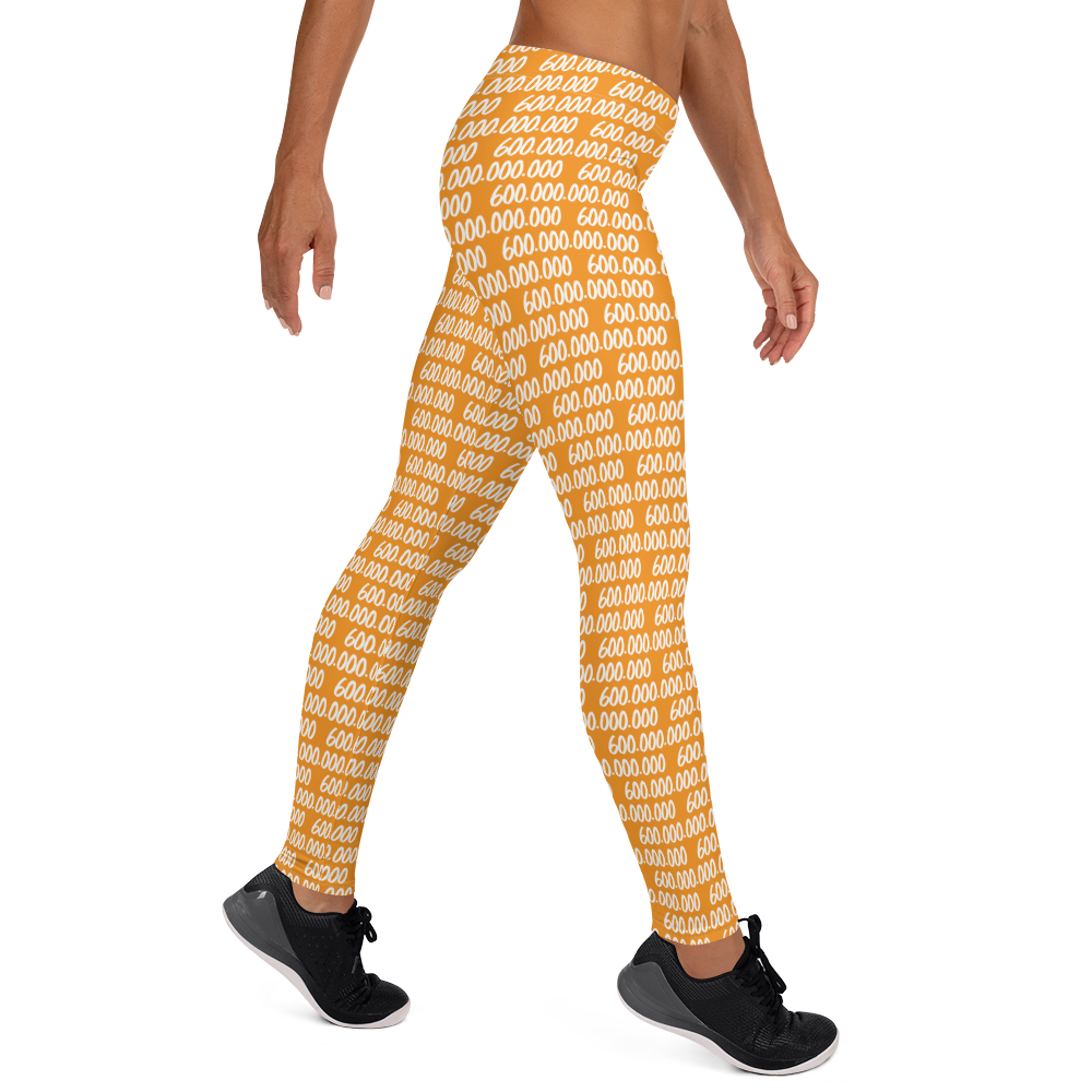 Side view of a woman wearing orange bitcoin leggings.