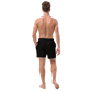 Back view of a man wearing a black bitcoin swim trunks.