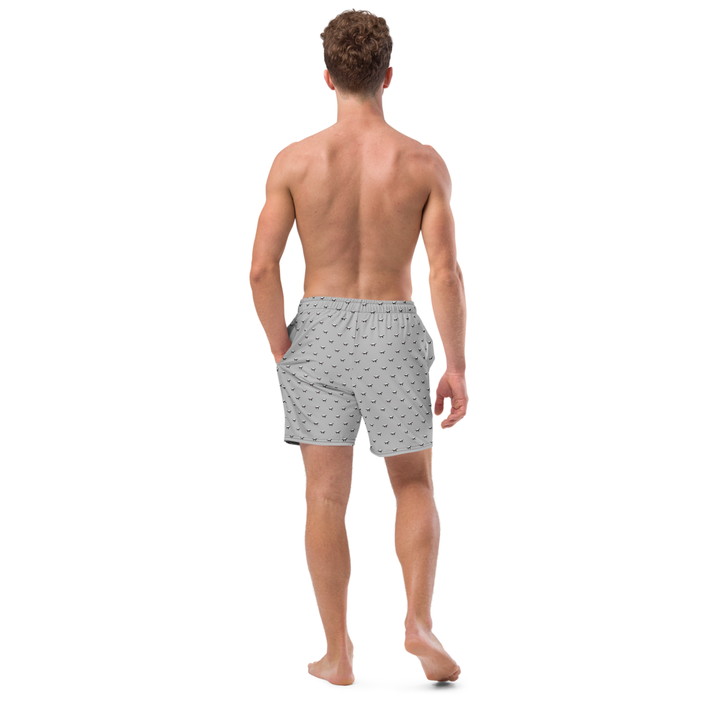 Back view of a man wearing a silver bitcoin swim trunks.