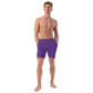 Front view of a man wearing a purple nostr swim trunks.