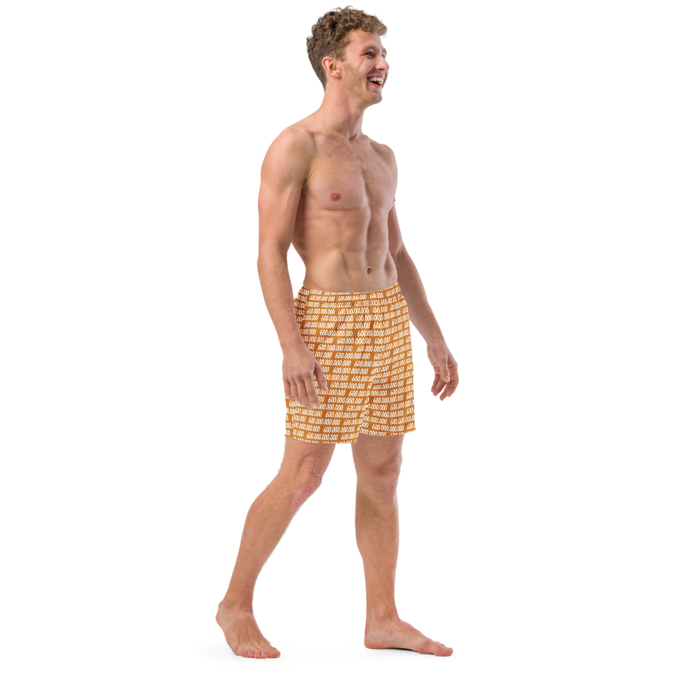 Side view of a man wearing an orange bitcoin swim trunks.