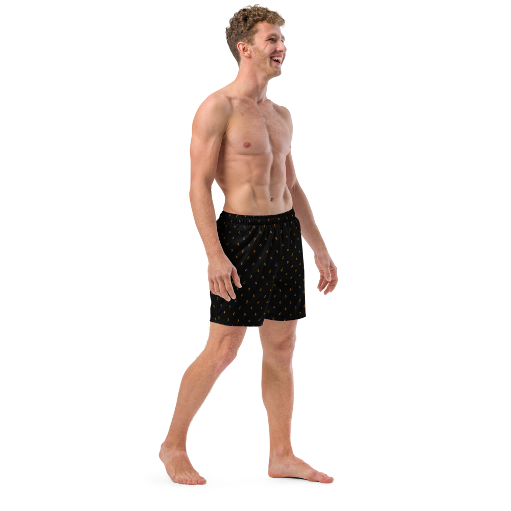 Side view of a man wearing a black bitcoin swim trunks.