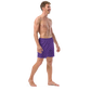 Side view of a man wearing a purple nostr swim trunks.