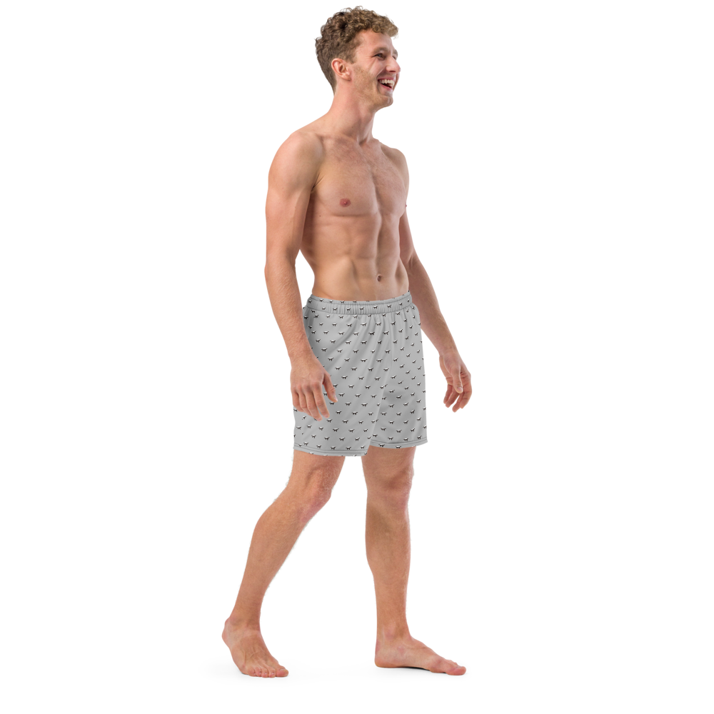 Side view of a man wearing a silver bitcoin swim trunks.