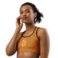 Front view of a woman wearing an orange bitcoin sports bra.