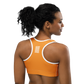 Back view of a woman wearing an orange bitcoin sports bra.