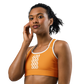 Front view of a woman wearing an orange bitcoin sports bra.