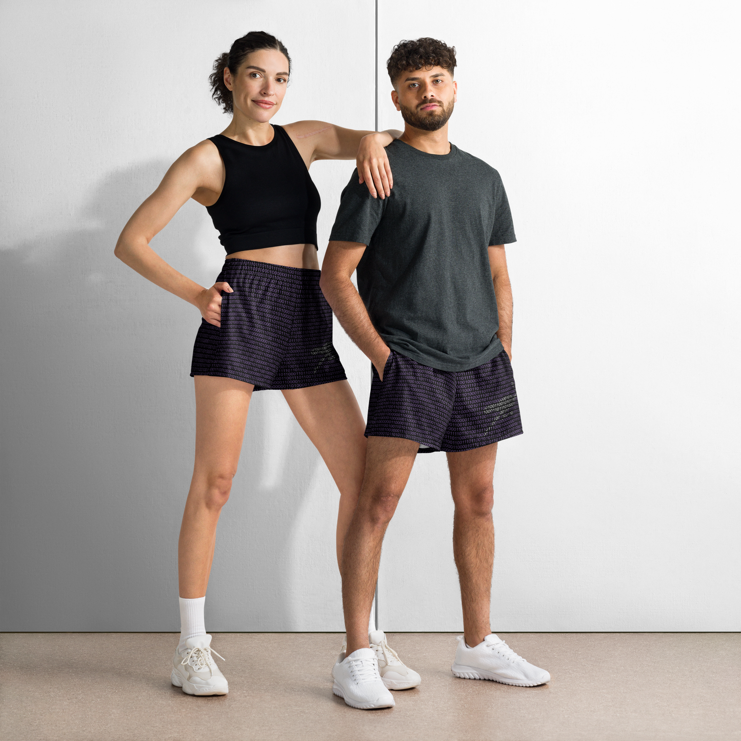 Front view of a man and a woman wearing black and purple nostr athletic shorts.