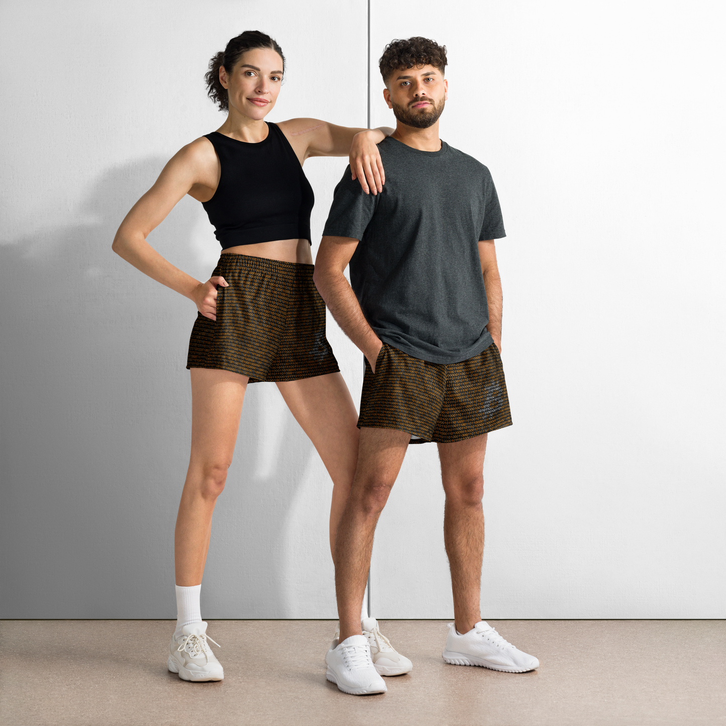 Front view of a man and a woman wearing black and orange bitcoin athletic shorts.