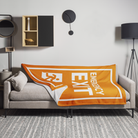 Emergency Exit Bitcoin throw blanket spread across a light grey sofa in a living room, showing the design in a home setting.
