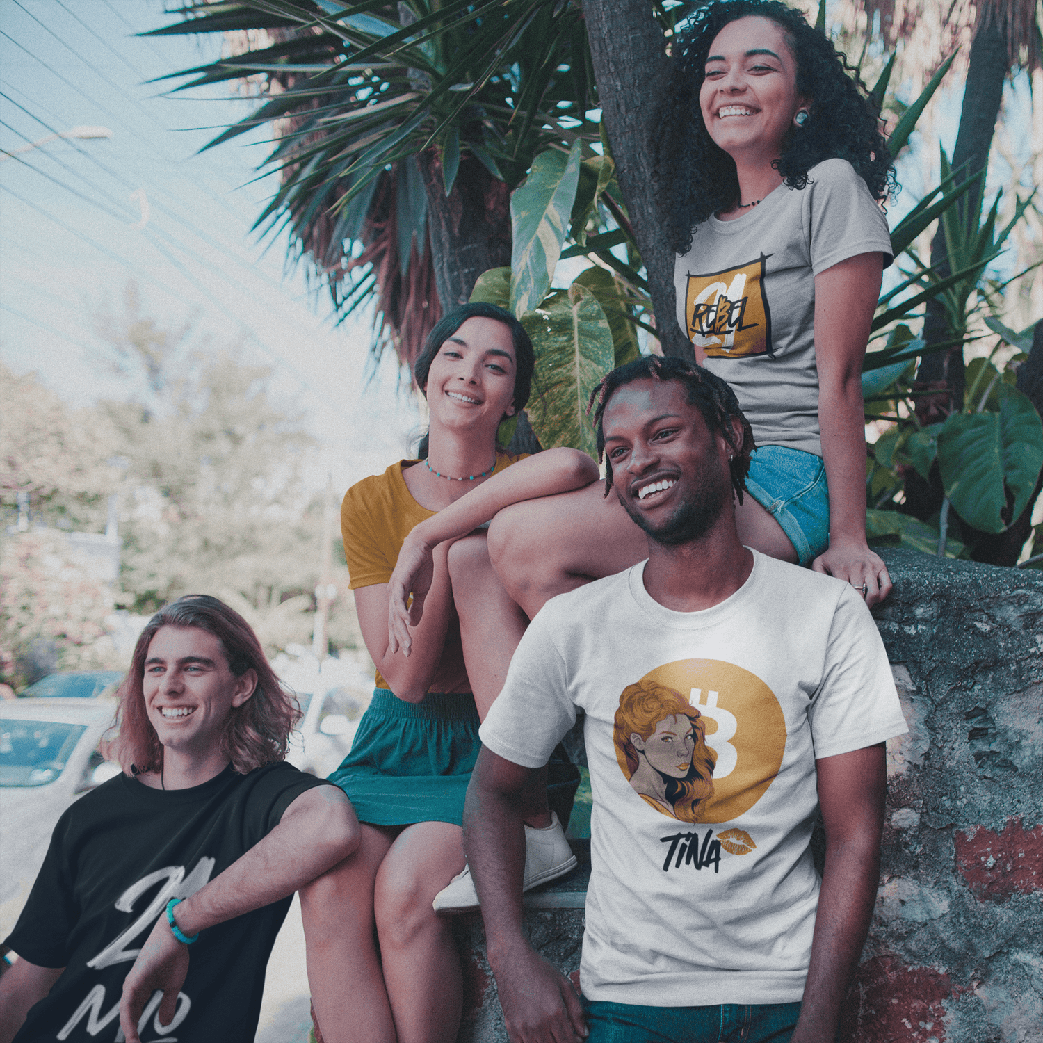 Interracial group of four friedns living the van life wearing bitcoin t-shirts under plants.