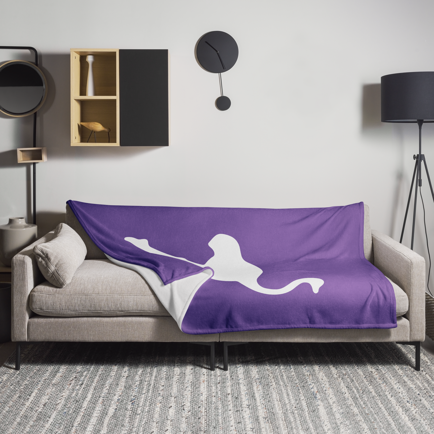 Nostrich Nostr throw blanket spread across a light grey sofa in a living room, showing the design in a home setting.