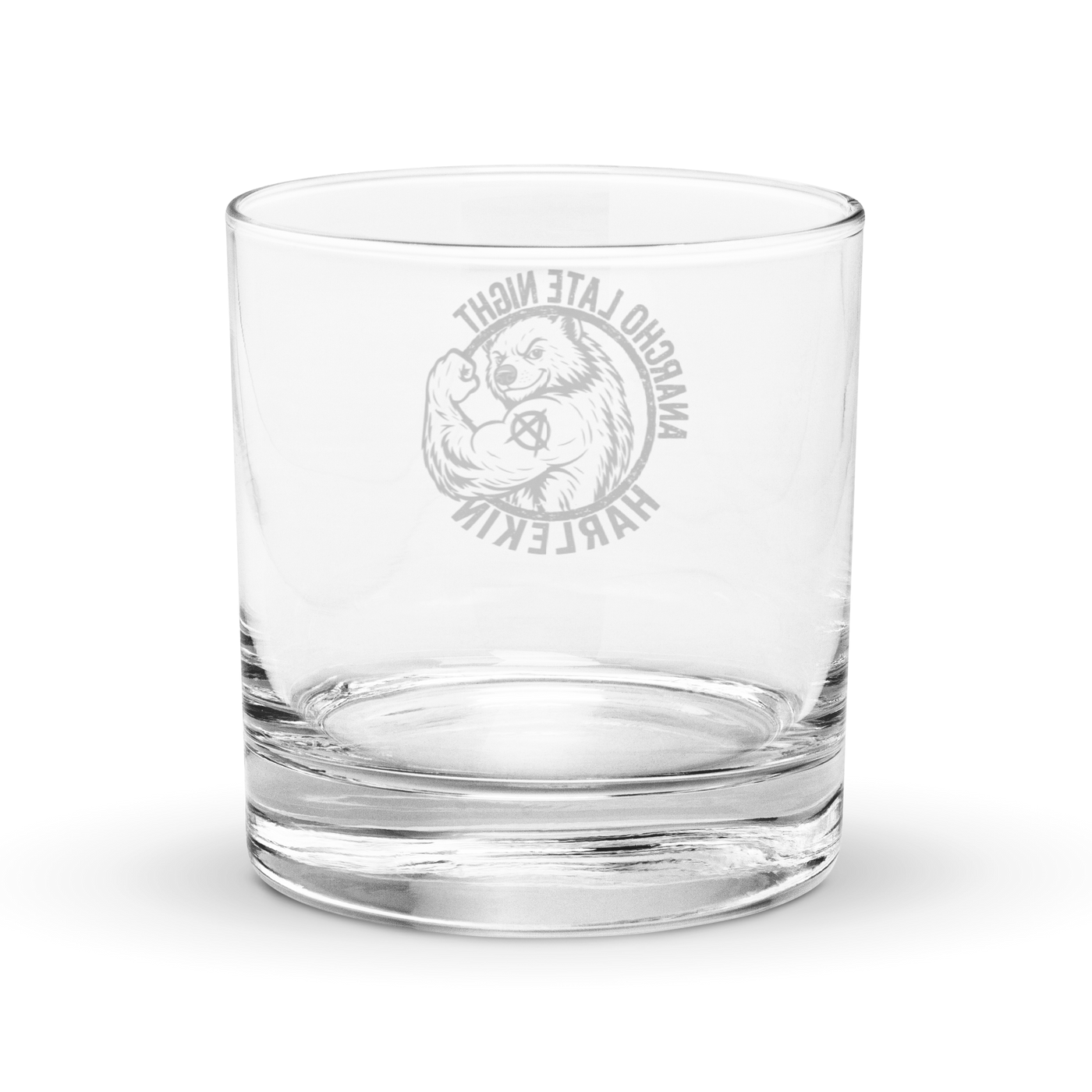 Anarcho Late Night Harlekin rocks glass, clear 10.5 oz whiskey glass with a round badge showing a grinning bear flexing its arm, an anarchy A on the biceps, the words ANARCHO LATE NIGHT arched above and HARLEKIN below, back view, the badge showing through the glass in mirror image.