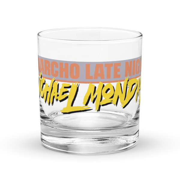 Michael Monday Anarcho Late Night rocks glass, clear 10.5 oz whiskey glass with a band running all the way around: ANARCHO LATE NIGHT in orange on grey above the name Michael Monday in yellow brush script, front view.