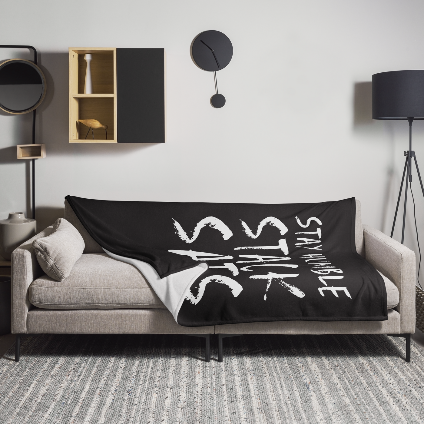 Stay Humble Stack Sats Bitcoin throw blanket spread across a light grey sofa in a living room, showing the design in a home setting.