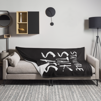 Stay Humble Stack Sats Bitcoin throw blanket spread across a light grey sofa in a living room, showing the design in a home setting.